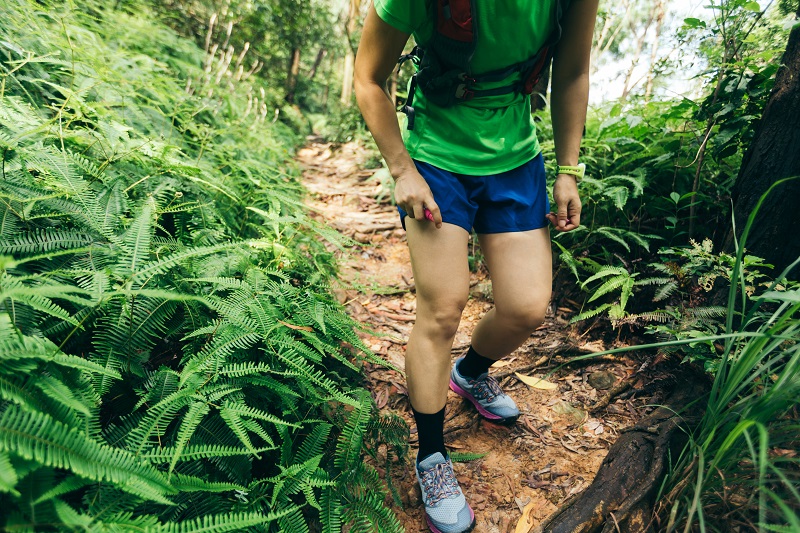 Woman trail runner spraying insect repellents on skin in summer tropical forest